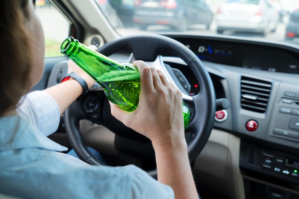 Stock illustration of a person drinking from a bottle while holding a steering wheel. This is not a photo of Cassidy Johnstone.